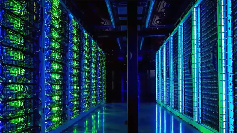 Two rows of server racks with glowing yellow and blue lights in a darkened server room.
