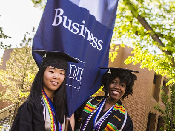 Graduates with a Business gonfalon at commencement