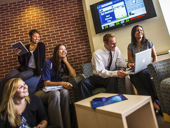Five students collaborate on a projects together dressed in business attire.