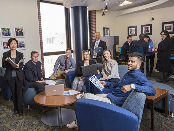 A bright room filled with management students and faculty all talking and interacting together.