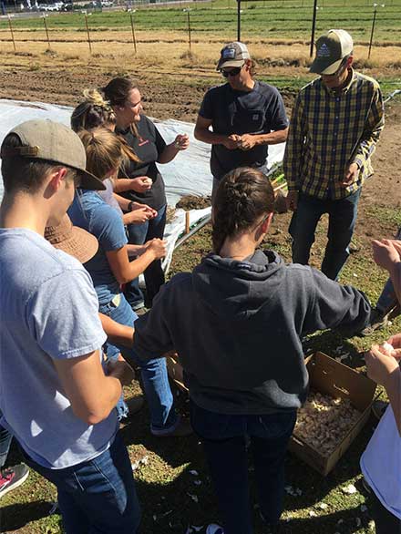 A group of people gathering around Charles Schembre and Felipe Barrios-Masias at Desert Farming Institute's farm on Valley Road in Reno.