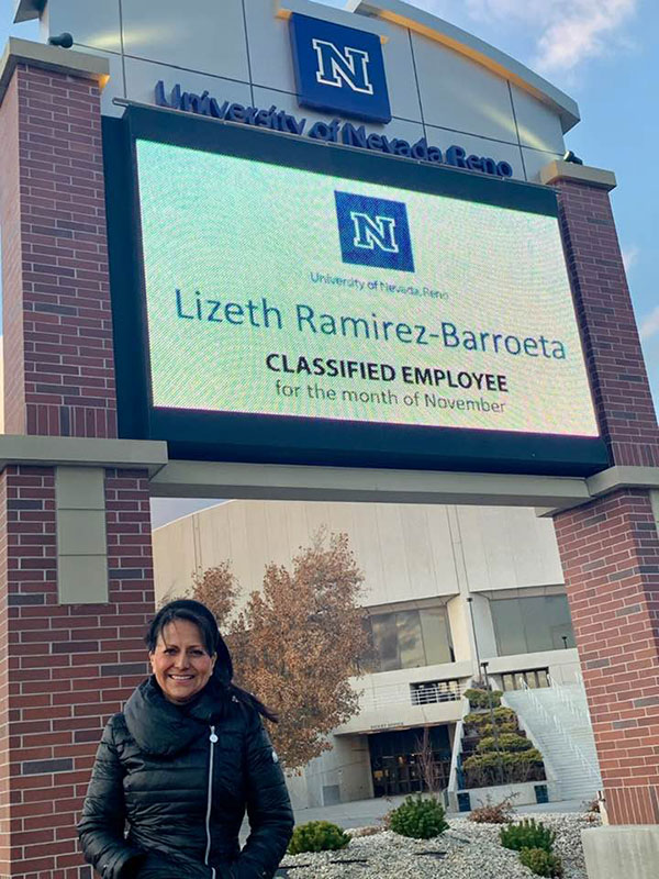 Lizeth Barroeta in a black puffy winter coat stands near the Lawlor marquee. It reads: Lizeth Ramirez-Barroeta. Classified employee for the month of November. 