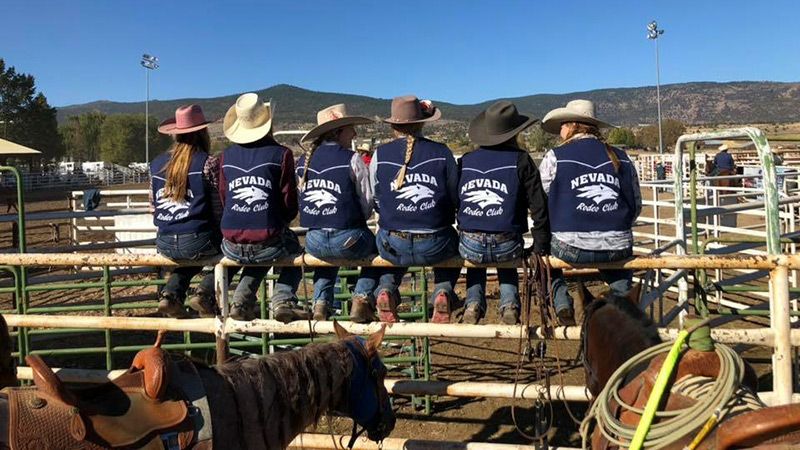rodeo team sitting on fence