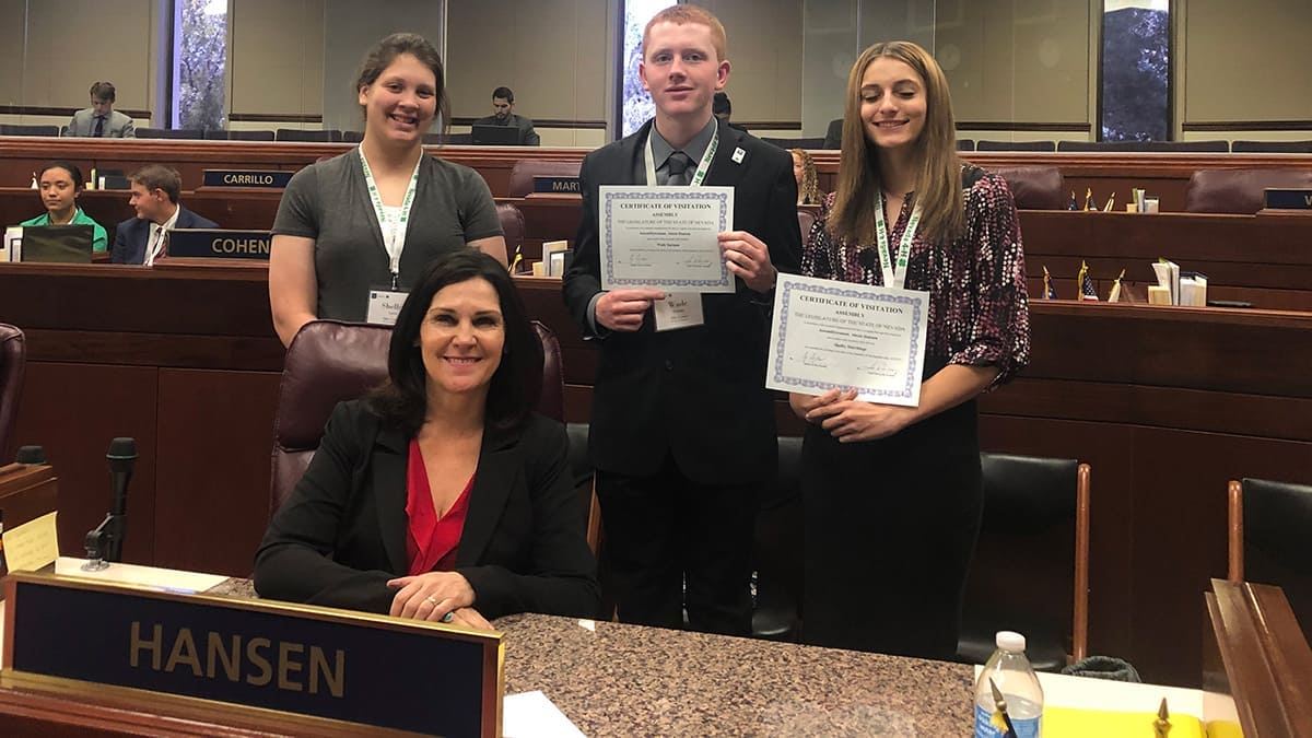 One 4-H boy and two 4-H girls standing with Assemblywoman Alexis Hansen