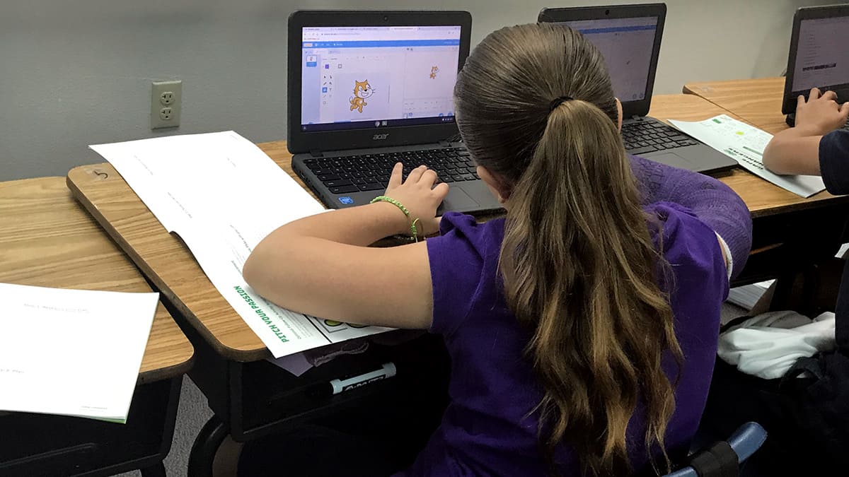girl coding a cat using the Scratch program language