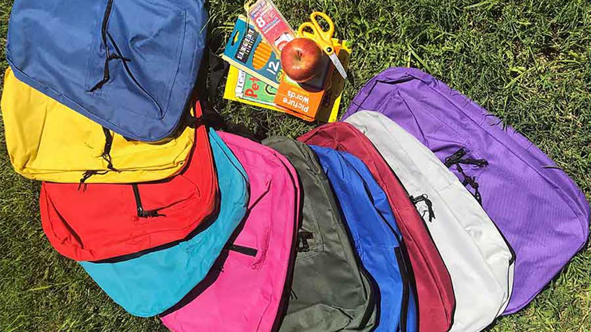Backpacks of different colors with school supplies 