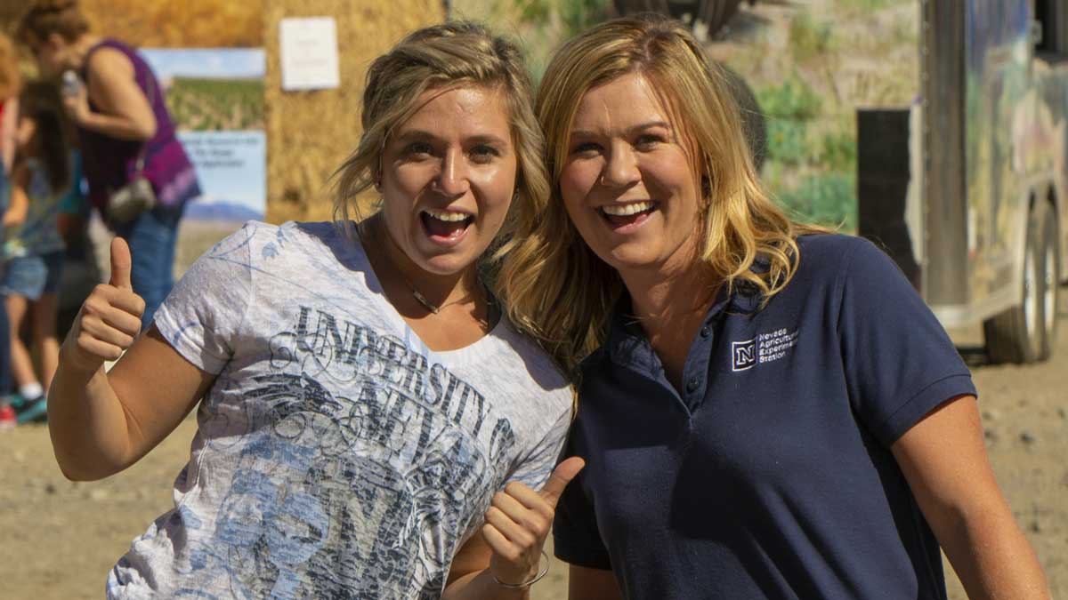 two women at field day giving a thumbs-up