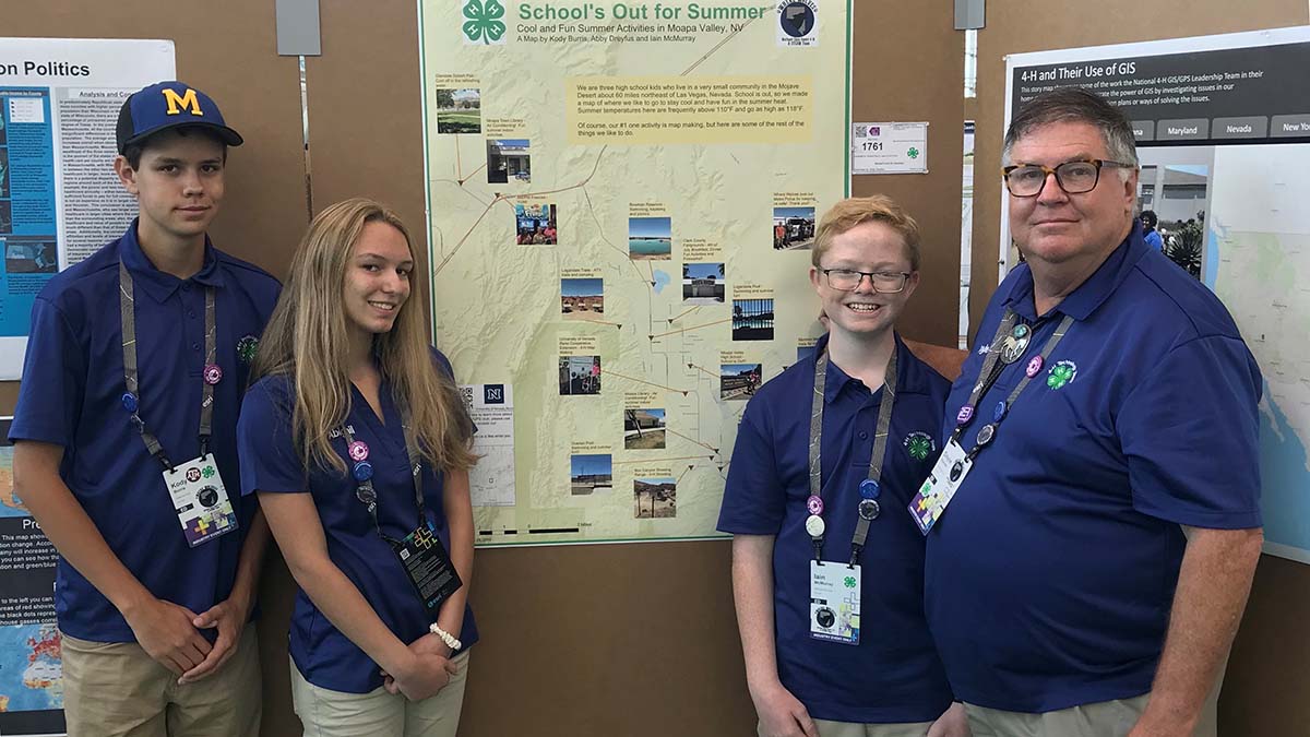 Three 4-H students and one adult with map