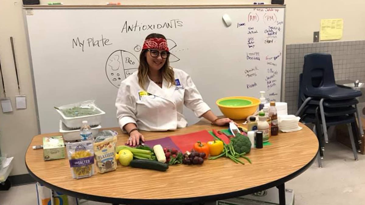 Susan McClain standing behind a table covered with fresh ingredients and cutting boards