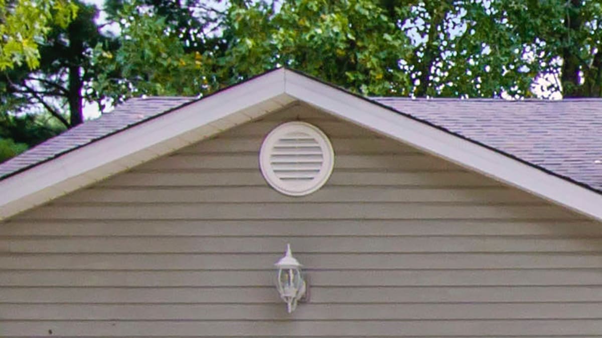a house with a circular vent outside near the roof