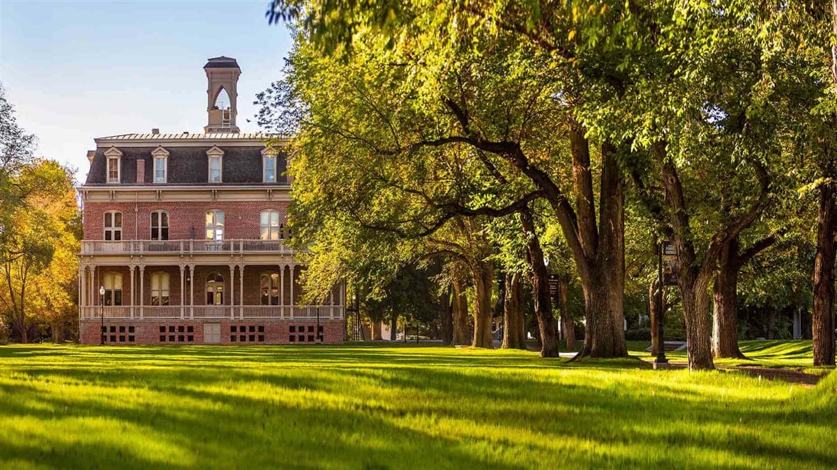 The historic Morrill Hall, a large, red-brick building, on the University's shaded, tree-lined Quad.