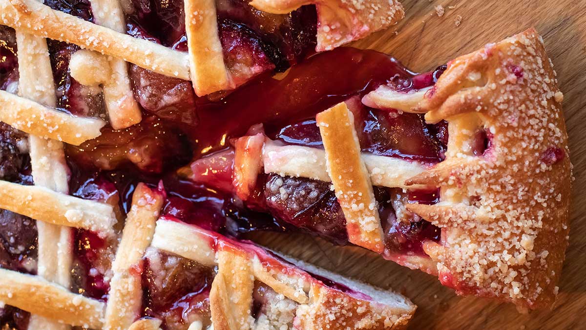 A freshly baked fruit pie with one slice out, showing its delicious interior