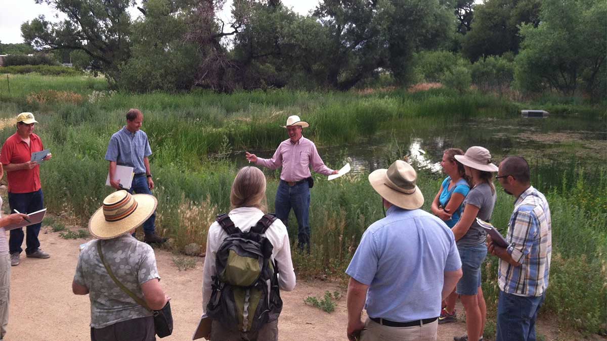 Sherm Swanson teaching a group of adults next to a pond