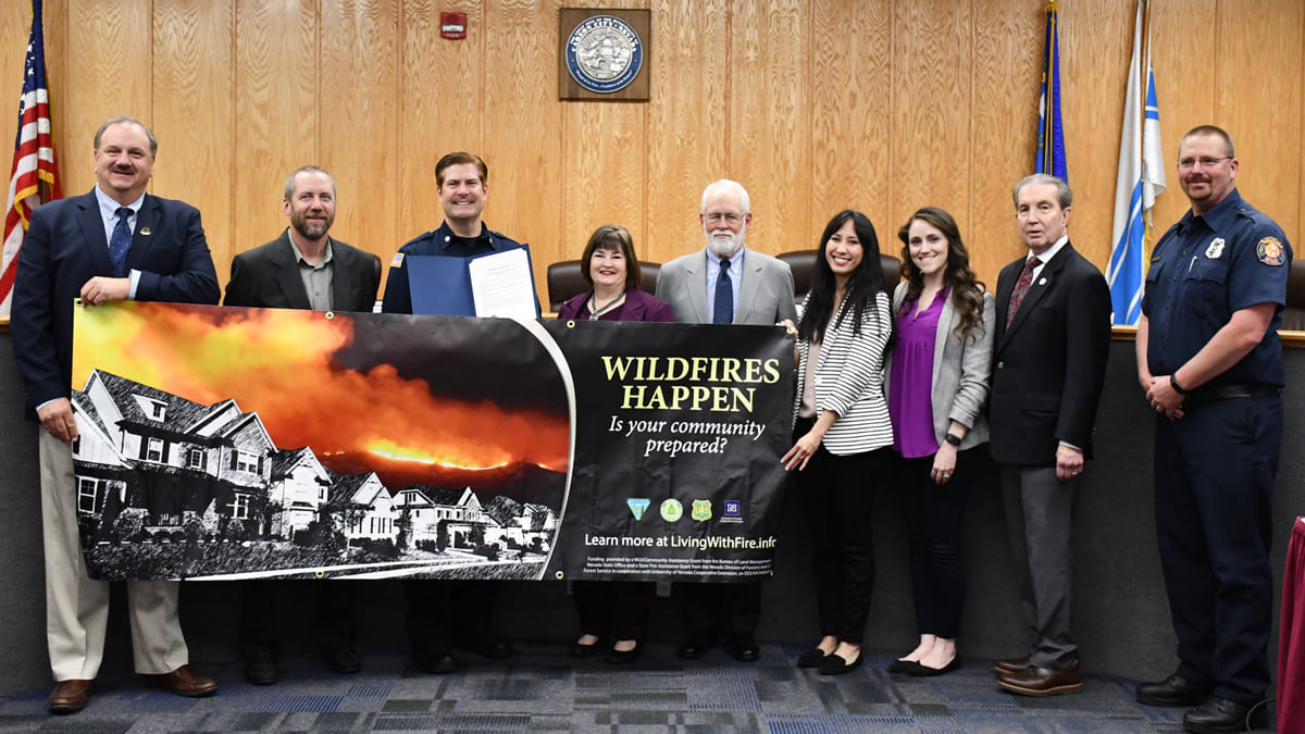Carson City mayor holding a Nevada Wildfire Awareness Month banner alongside fire department and Living With Fire staff