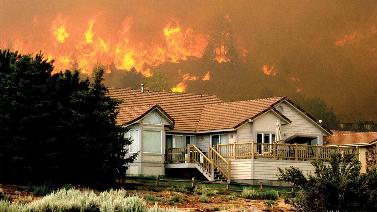 A burning hillside behind a house