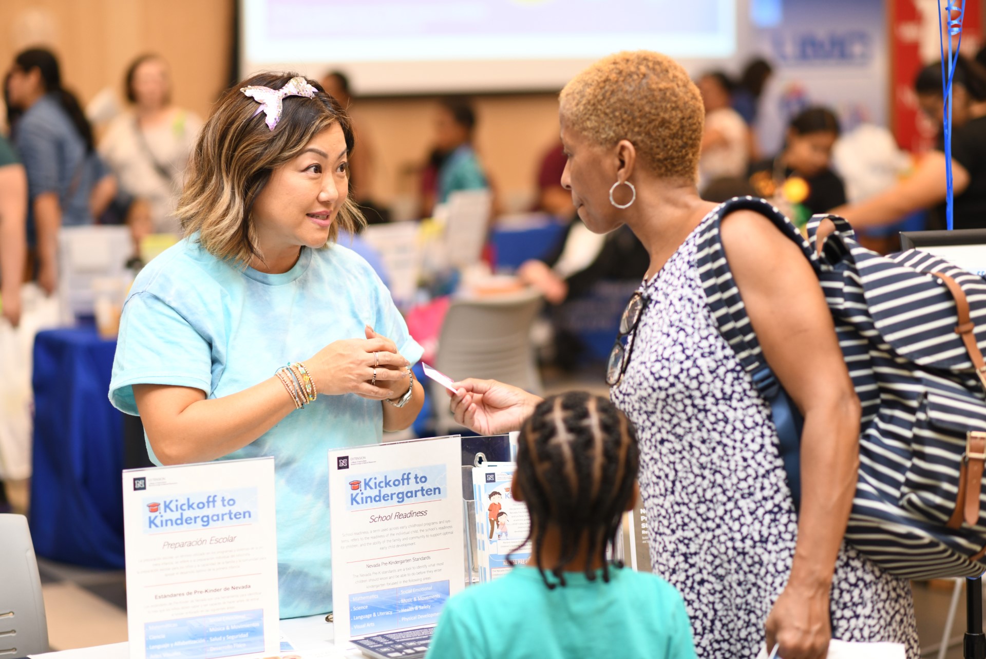 Two adults and a child talking at a booth.