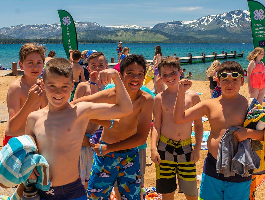 A group of campers in bathing suits standing on the beach.
