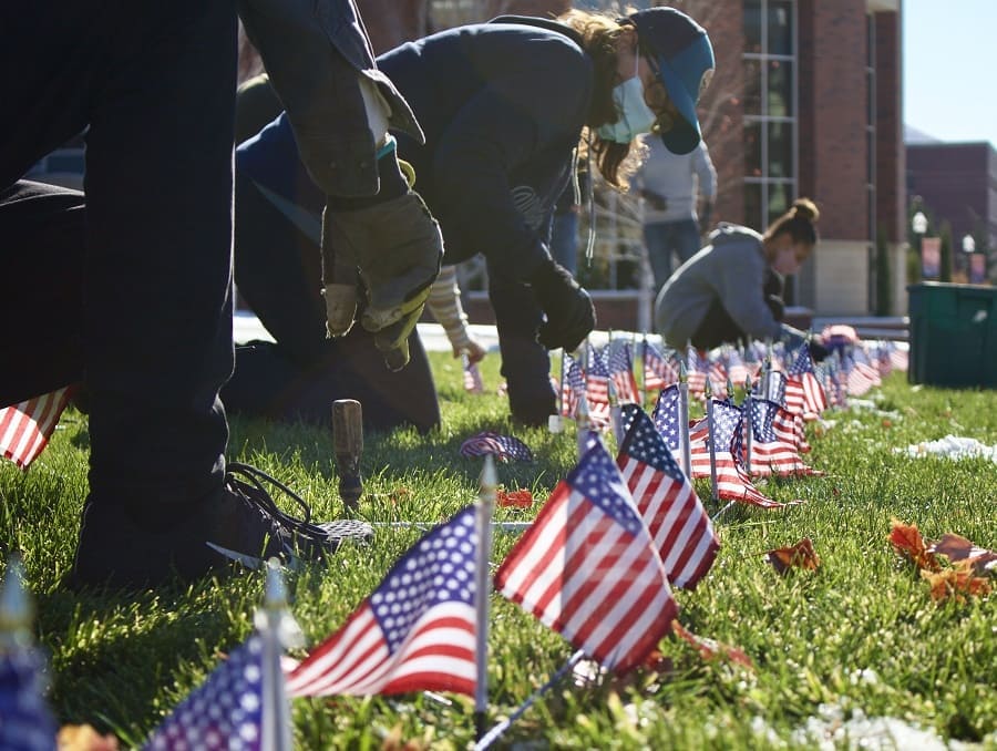 Socially distanced masked students bundled up against the cold planting 2,000 flags in front of the Joe Crowley Student Union