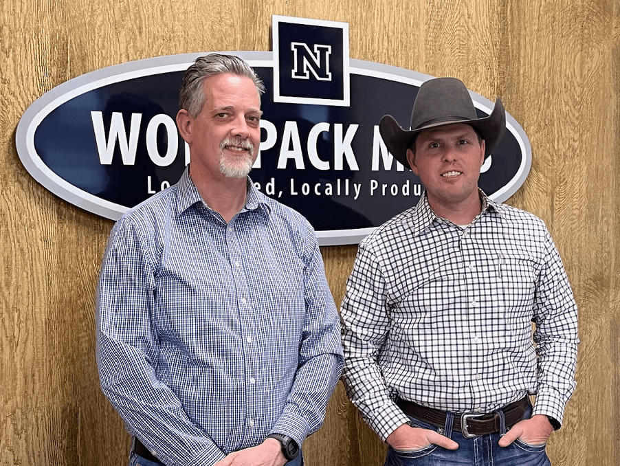 Tom Kulas, operations manager, and JD Hoagland, consultant standing in front of a Wolf Pack Meats sign.