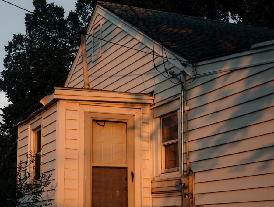 A front porch of a white house as the sun is going down.