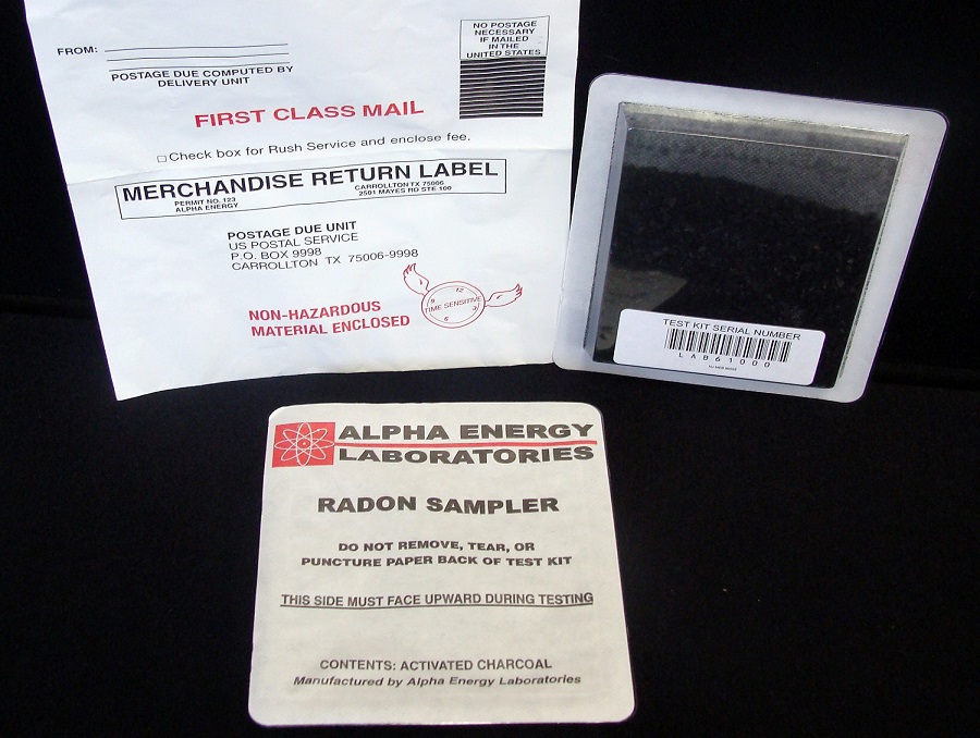 A radon sampler test kit sitting next to a first class mail envelope.