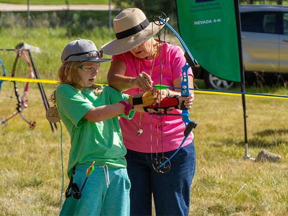 An adult helping a youth with a bow