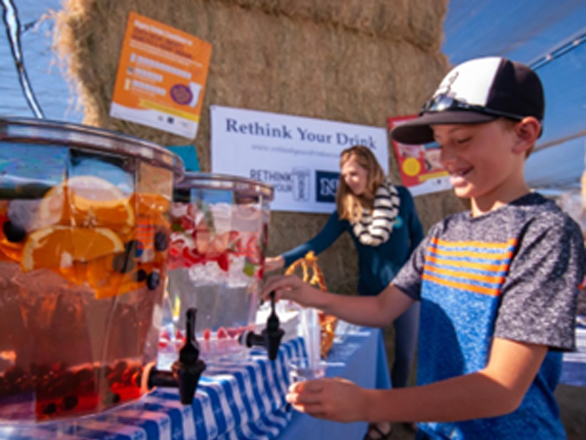 A child pours a drink from a drink stand.
