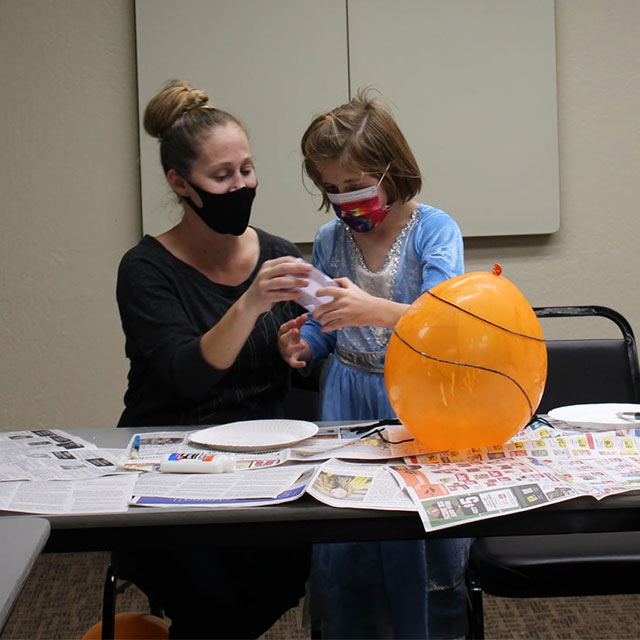 A 4-H volunteer helps a 4-H'er make spiderwebs