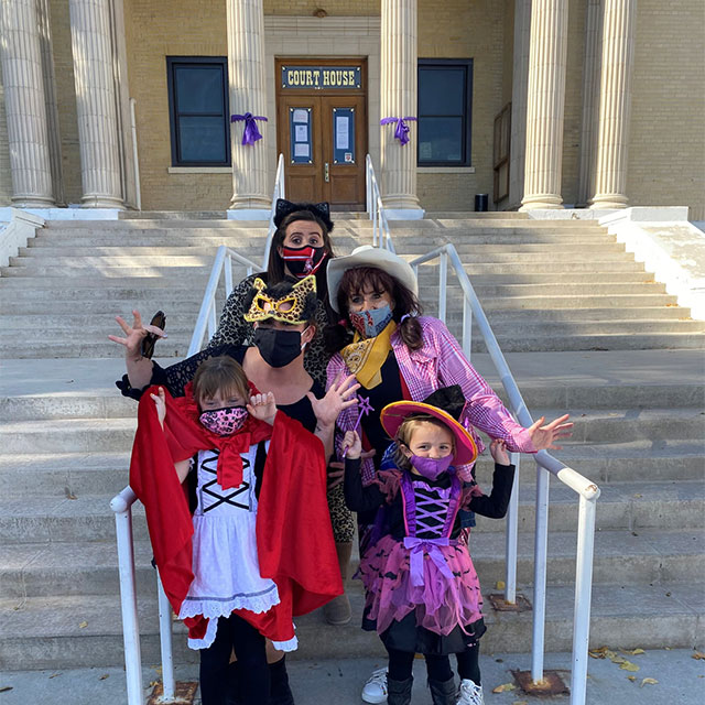 A family in halloween costumes on the steps of the courthouse