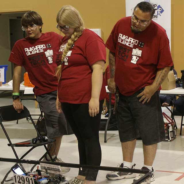 Jason Riendeau in an Awkward Silence 4-H Club shirt looks on as his club competes in a robotics competition