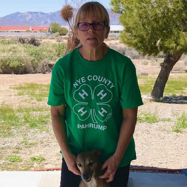 Laurie Tully in a Nye County 4-H shirt and working with a dog