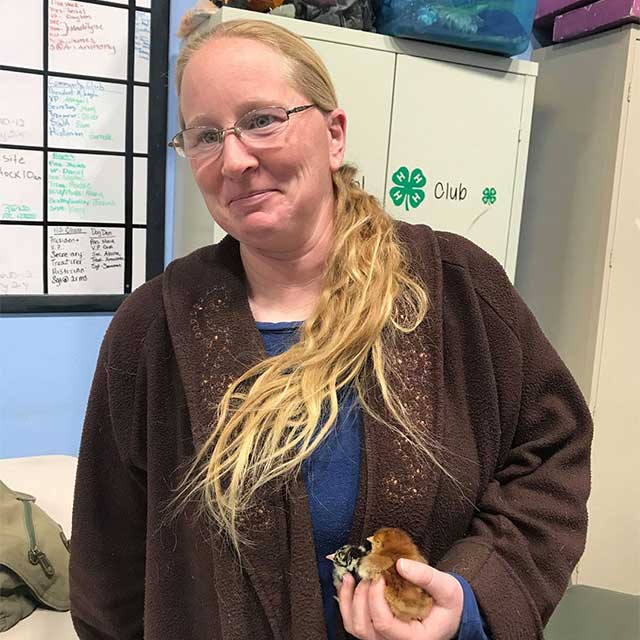 Mindi Mulcahey in the 4-H office holding two baby chicks