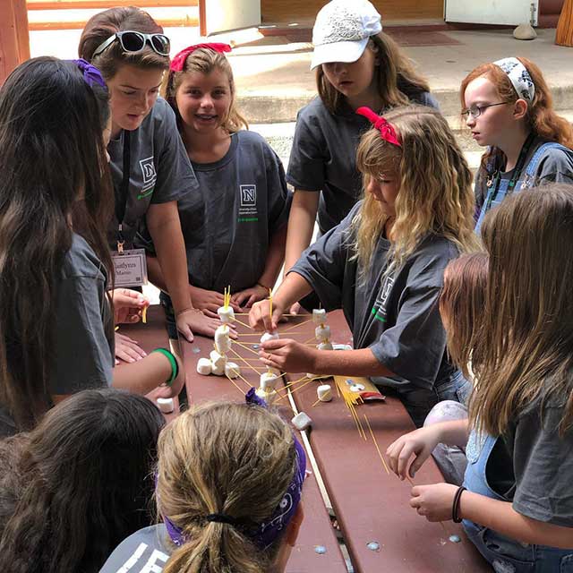 Group of campers working together to build a tower