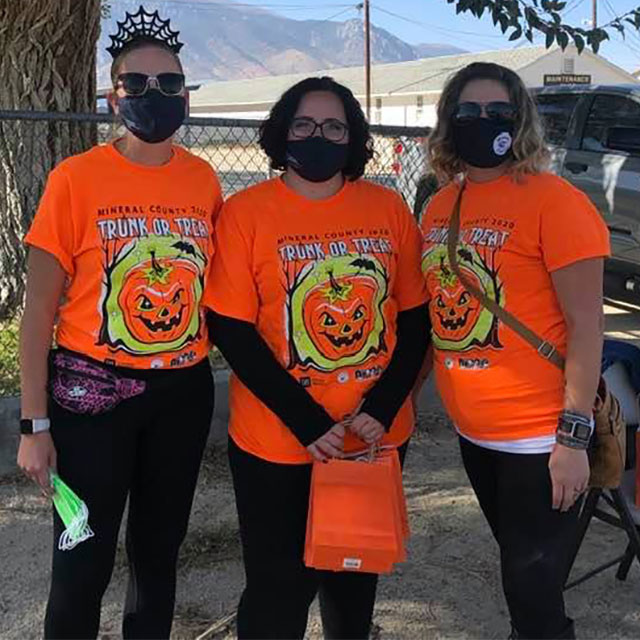 Adults in Trunk or Treat shirts and costumes poses at the event