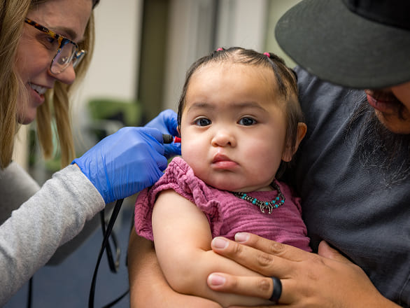 A baby being held by her father gets an exam