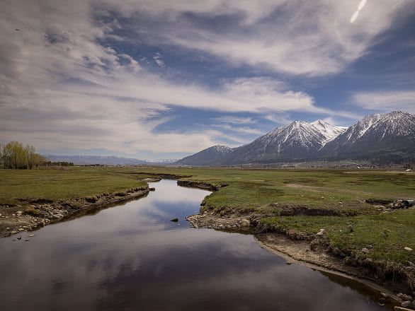 A river runs to the horizon through a green field near Minden, Nevada