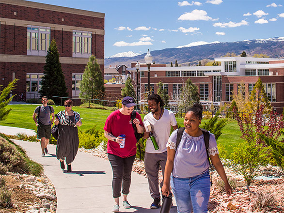 Students walking down path smiling in front of University building