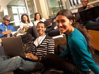 Five students smiling and using their laptops