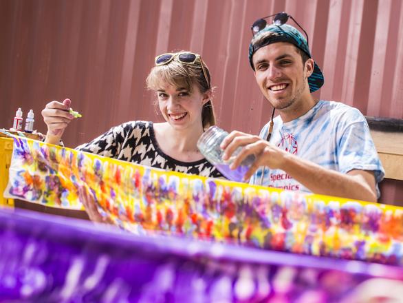 Two students working with fabric and bold orange and purple paint.