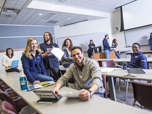 A group of 10 people mingling in a classroom.