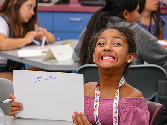 Young child holding up white board with writing