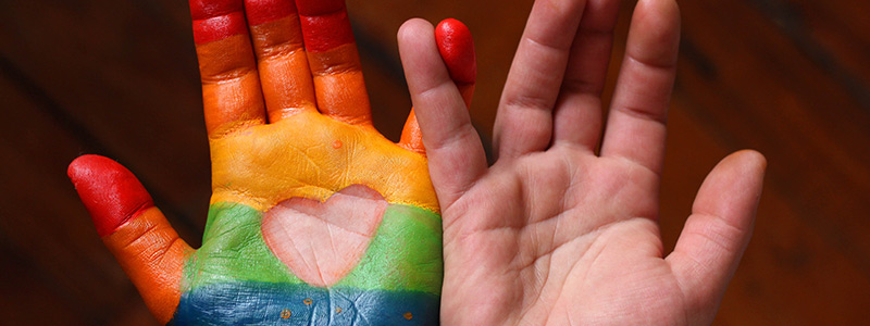 Two hands painted in rainbow paint