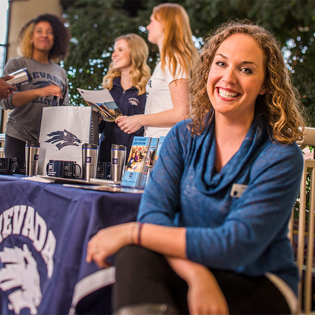 Advisor smiling next to Wolf Pack table