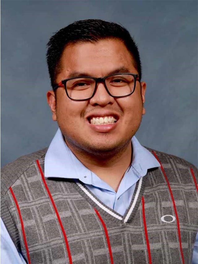 Allan Joseph Romero, shown from the chest up, in front of a gray background.