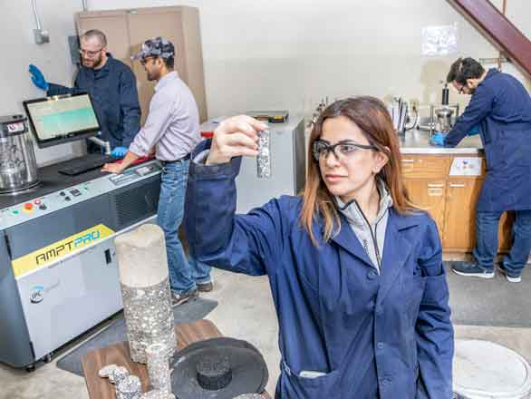 A student inspects a pavement sample while other students work in the pavements engineering lab
