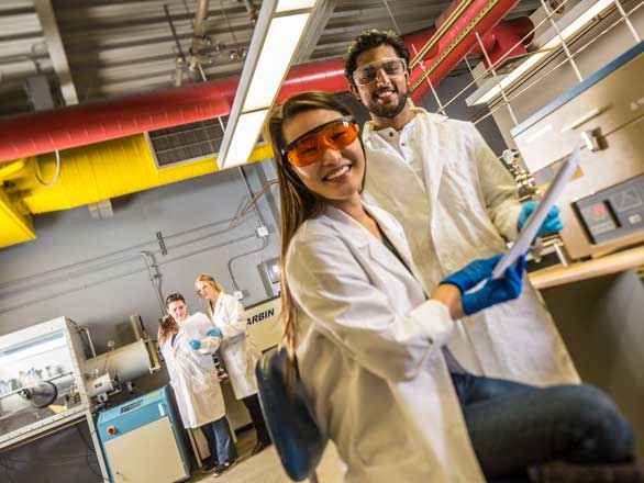 Four students in lab coats in a battery engineering lab
