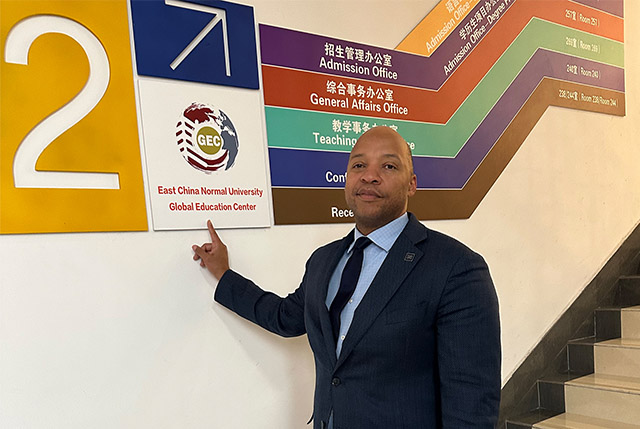 Erick Jones pointing to a sign that reads East China Normal University Global Education Center.