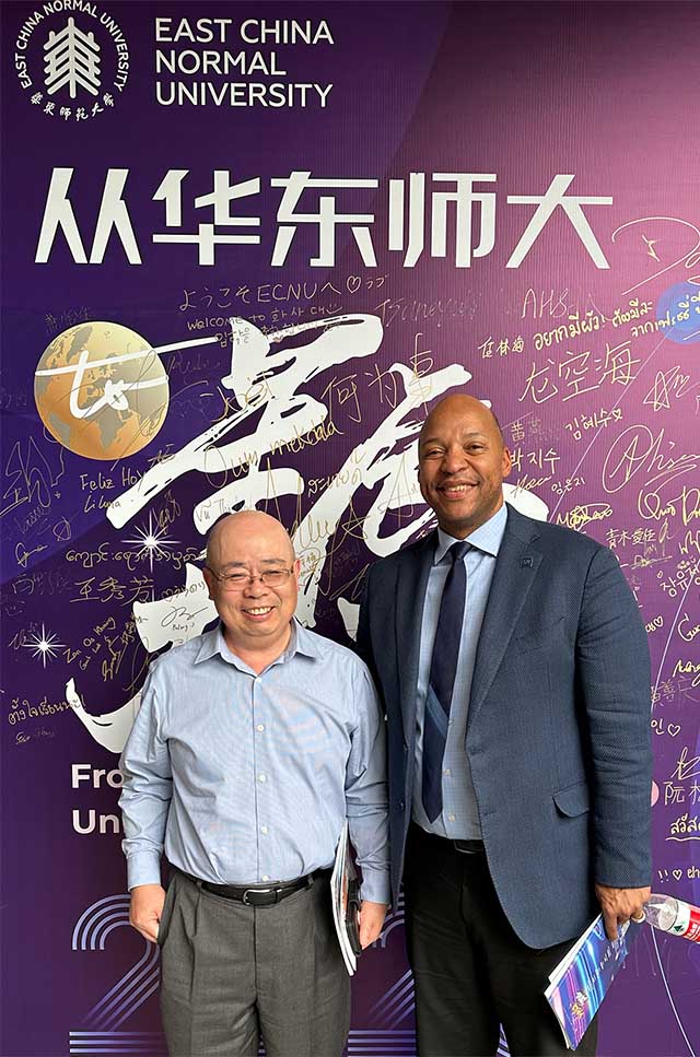 Business Professor Chunlin Liu and Engineering Dean Erick Jones standing before a backdrop that reads East China Normal University.