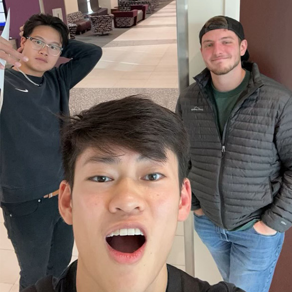 Three male students standing in a hallway