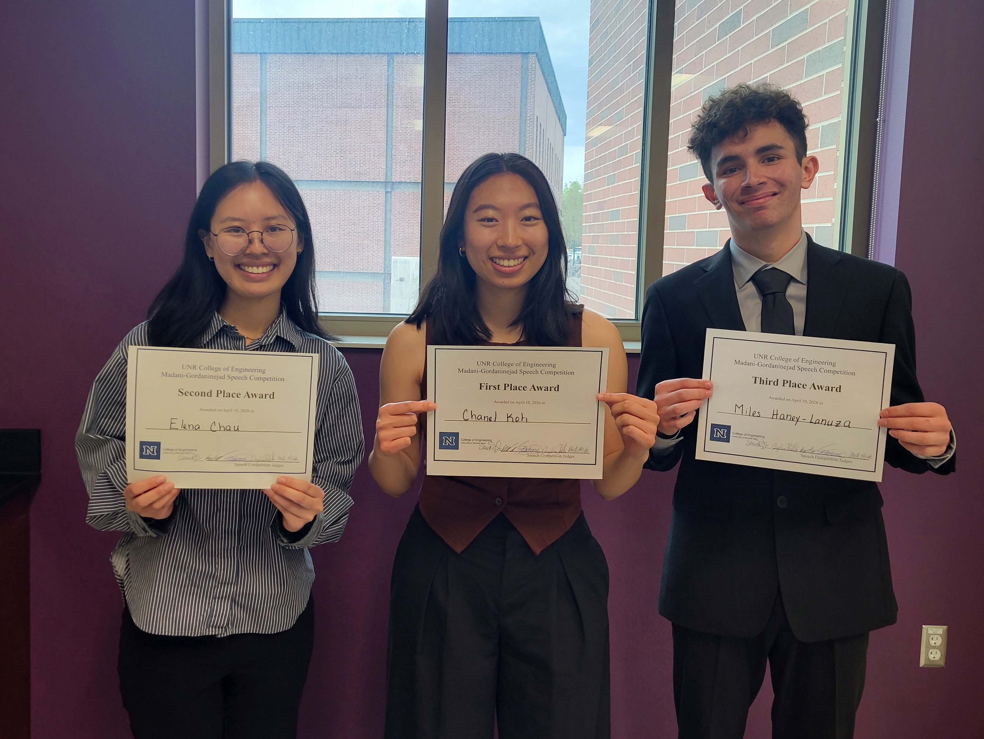 Two women and a man stand in a row, each holding up certificates.